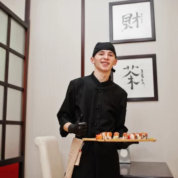 Le chef professionnel porte en noir avec des sushis et des petits pains dans un restaurant de cuisine traditionnelle japonaise.