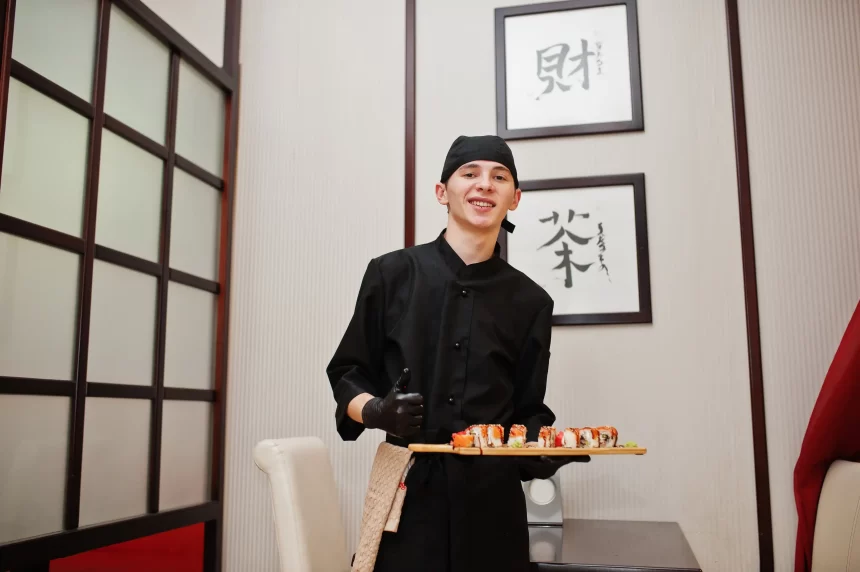 Le chef professionnel porte en noir avec des sushis et des petits pains dans un restaurant de cuisine traditionnelle japonaise.